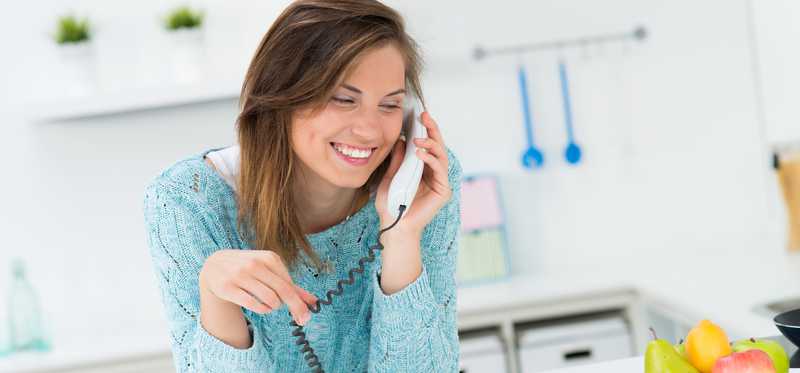 A woman talking on the phone in the kitchen