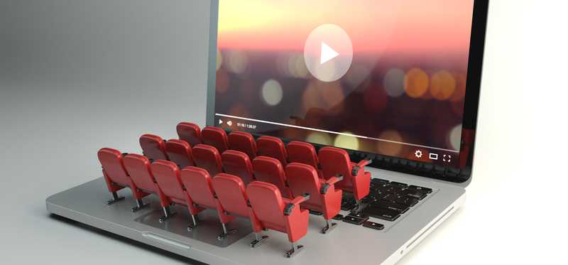 A laptop with mini movie seats on its keyboard.