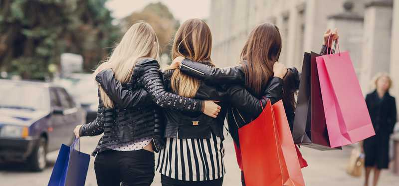 Three young women walking together with shopping bags.