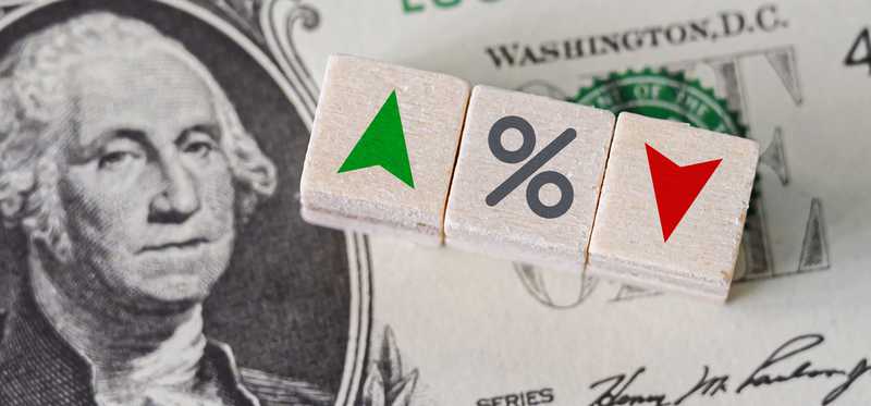 Depiction of interest rates with dollar bill and blocks with up and down arrows and percent symbol.