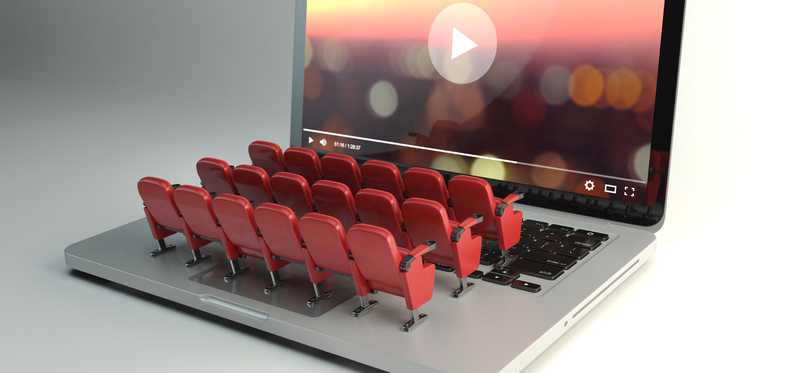 Theater seats arranged on a laptop keyboard facing the screen that is streaming a video.