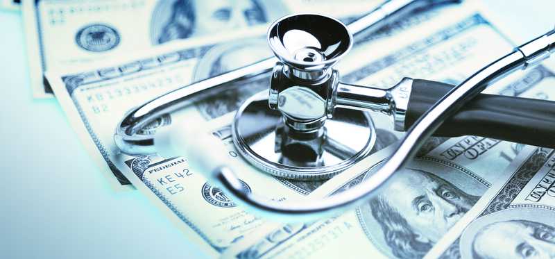 A fan of hundred dollar bills with a stethoscope on top.