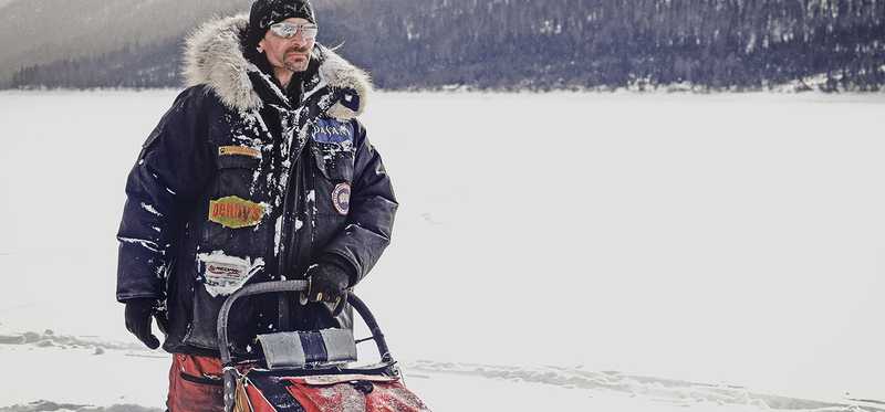 Man using a snowblower outdoors in winter gear.