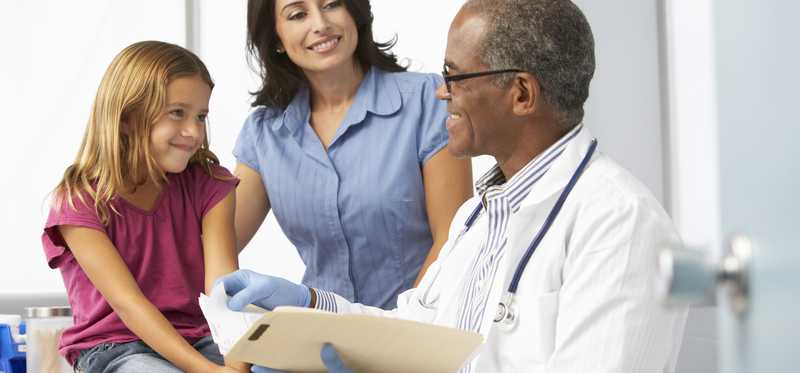 A doctor talking to a young girl and her mother.