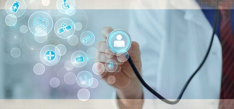 Doctor holding a stethoscope to a digital screen with various images on it.