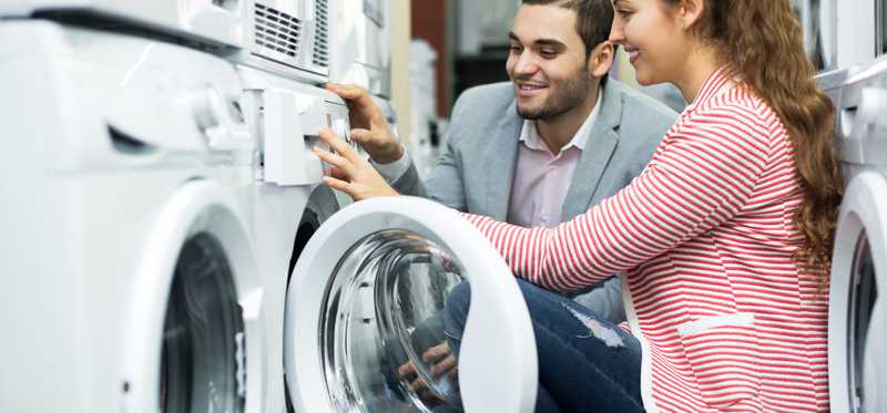 Young couple uses washers at a laundromat.