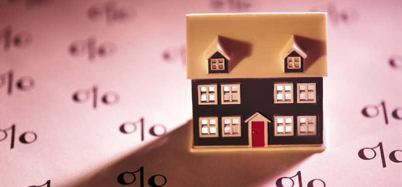 Model house on top of a sheet of paper filled with percentage signs.