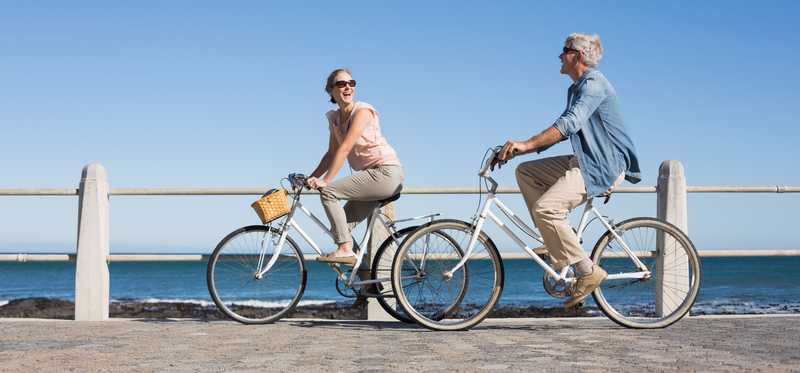A couple riding bikes on a boardwalk.