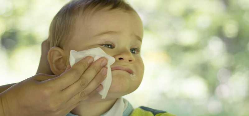 Woman wipes her toddler's face.