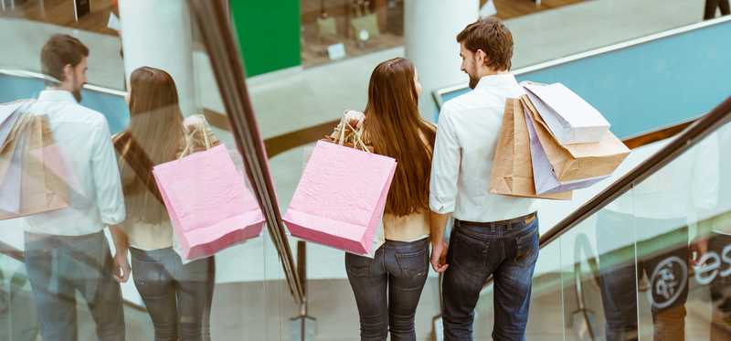 Two people on an escalator at a shopping mall.