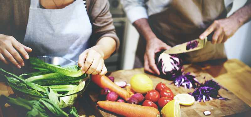 A man and woman prepare fresh produce.