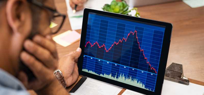 Person looking at a tablet showing a stock chart going down.