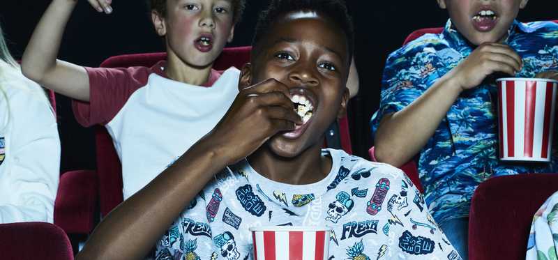 Children eating popcorn in a movie theater.