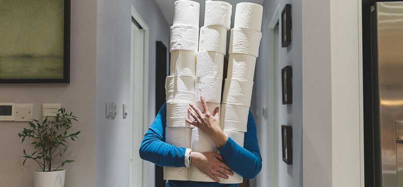 Man carrying several stacks of toilet paper rolls