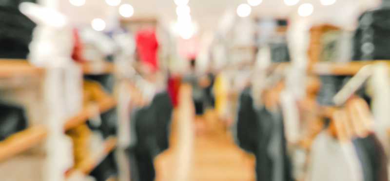 A blurred image of the inside of a retail clothing store.