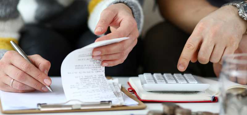 Two people working on calculator and writing notes.