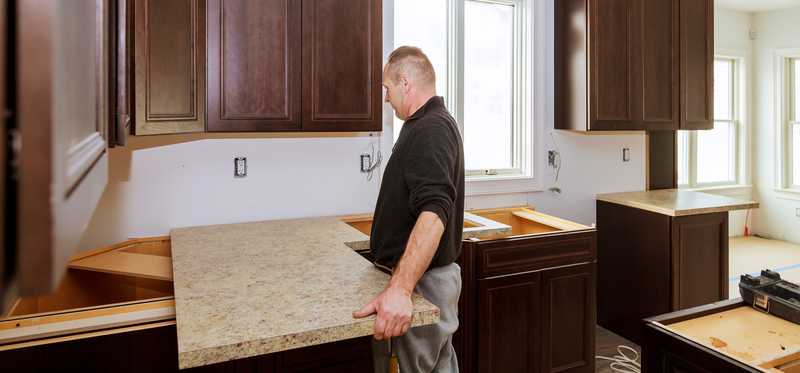 Person installing a new countertop in a kitchen.