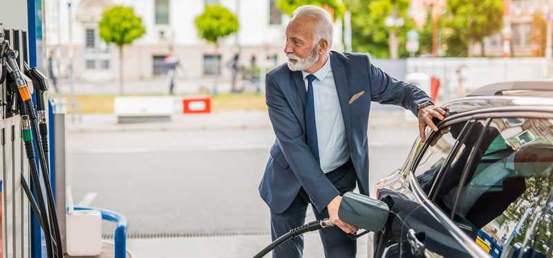 Person in suit is pumping gas.
