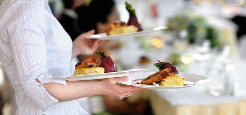 A waitperson carrying plates of food.