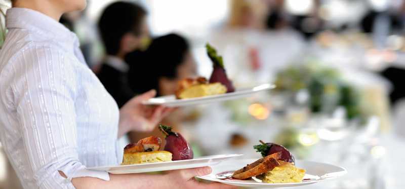 A waitperson carrying plates of food.