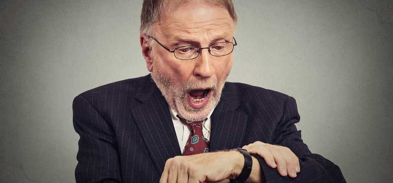 Mature man shocked looking at wrist watch.