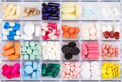 A pill case full of different colored and shaped pills.