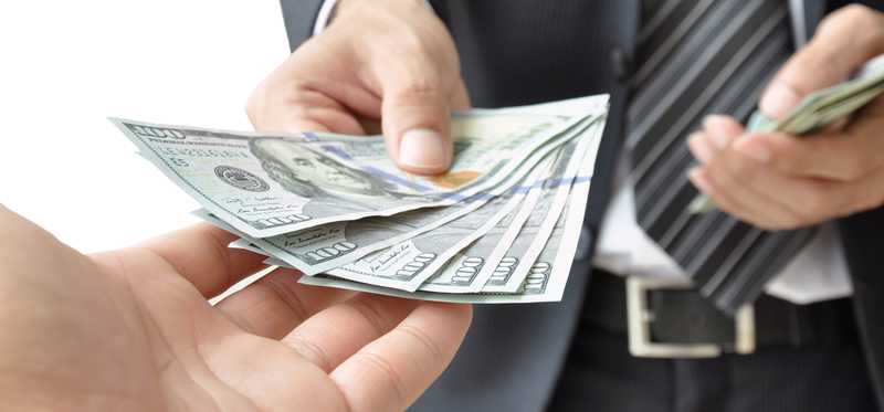 Large bills exchanging hands between businesspeople.