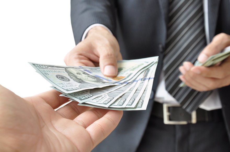Large bills exchanging hands between businesspeople.