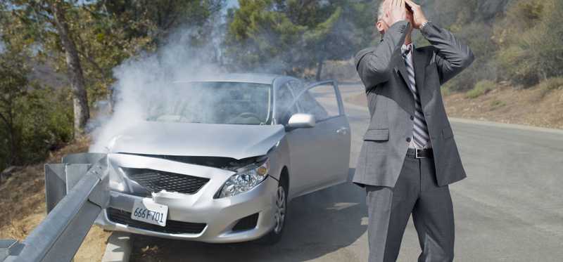 Distraught man standing in front of his wrecked vehicle.