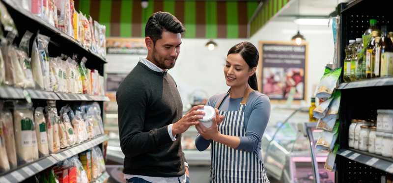 Person helping a customer in a store aisle.