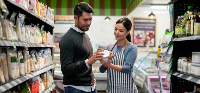 Person helping a customer in a store aisle.