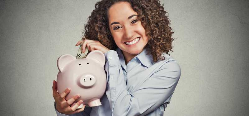 A woman smiling holding a large piggy bank.