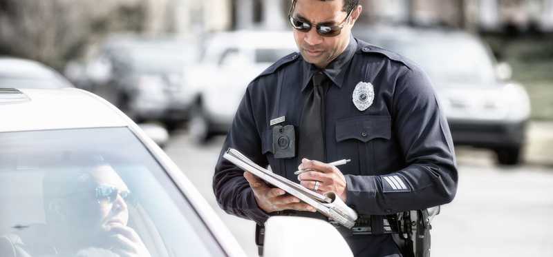 Police officer writing ticket for motorist.