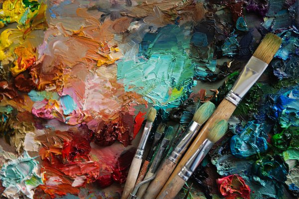 Paint brushes lay atop a painting in progress.