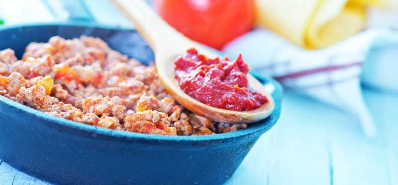 Beef in a pan with a spoon of salsa.