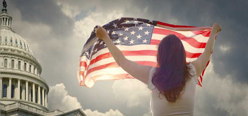 Person holding American flag outside U.S. Capitol.