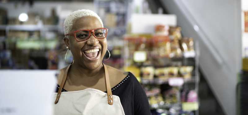 Cashier smiling and wearing red glasses.