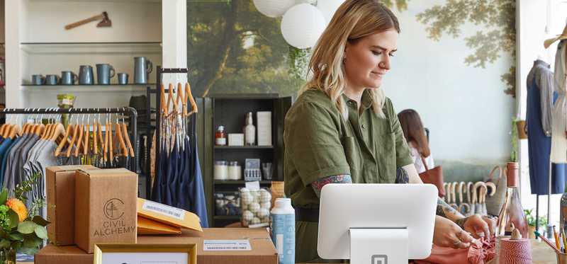 Employee working in store using Square payments system.