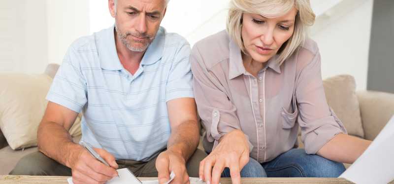Two people looking at paperwork and using a calculator.