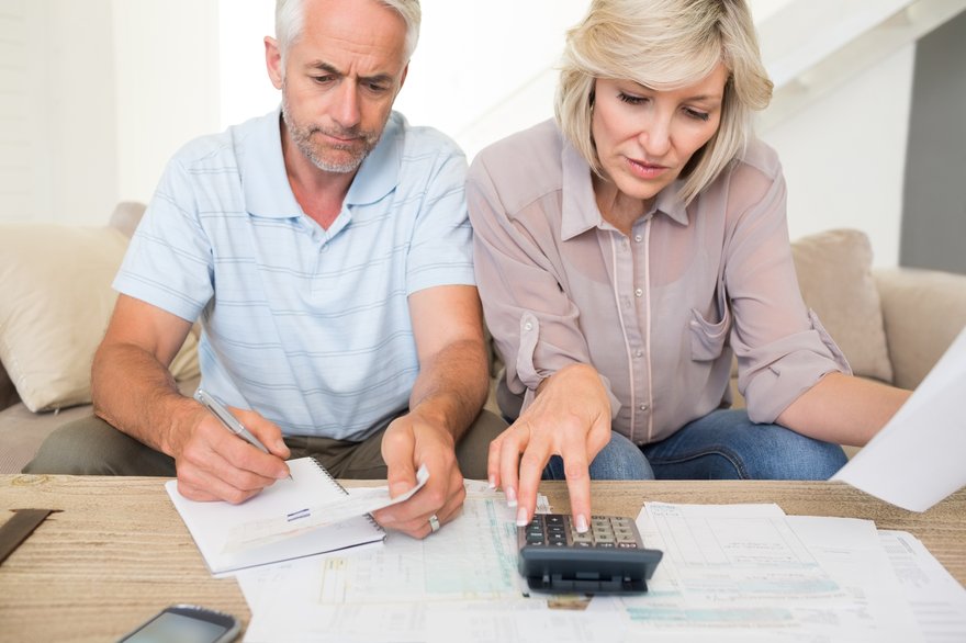 Two people looking at paperwork and using a calculator.