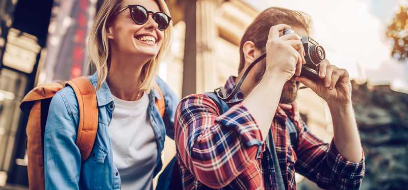 Tourists with backpack and taking photo with camera
