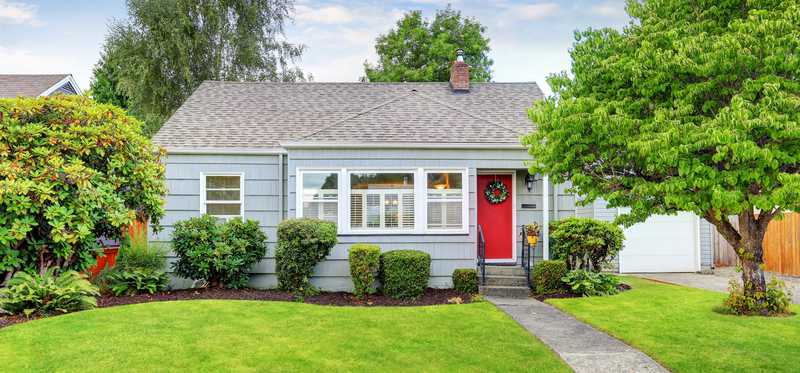 A small house with a front yard in a suburban neighborhood.
