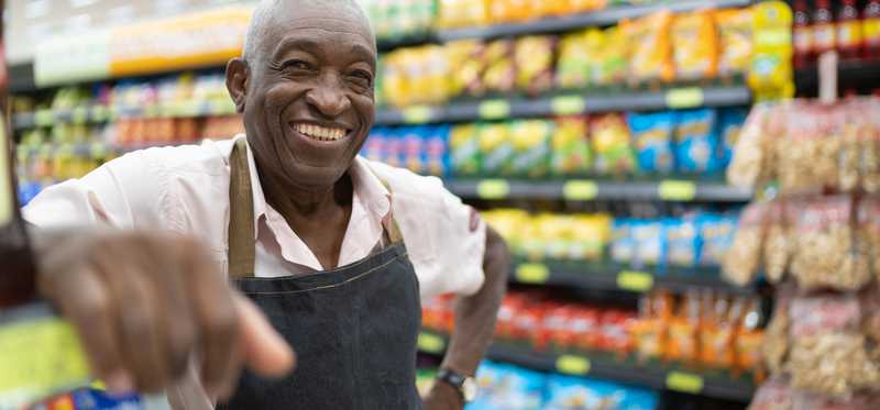 Person wearing an apron in a supermarket smiles.