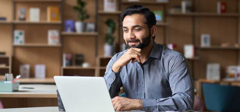 Smiling person working on laptop in modern office.