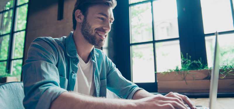 Smiling person typing on a laptop.