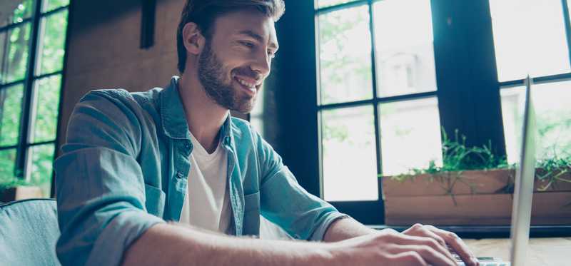 Smiling person typing on laptop.