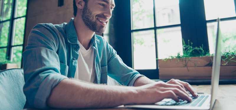 Smiling man typing on laptop