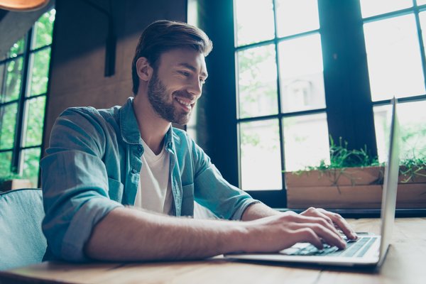 Smiling person typing on laptop.
