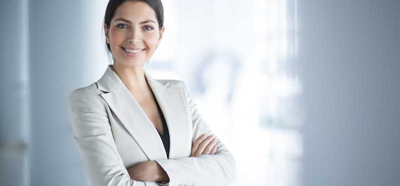 Smiling professional woman standing with arms crossed.