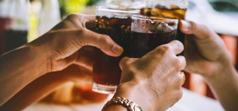 People hold up glasses of soda.